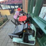 Nancy standing behind her scooter among several others at Disney, highlighting real-life visibility challenges for senior guests.